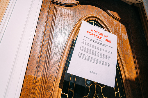 Low Angle Shot of a Paper Foreclosure Notice Taped to the Front Door of a Home in a Residential Suburban Neighborhood