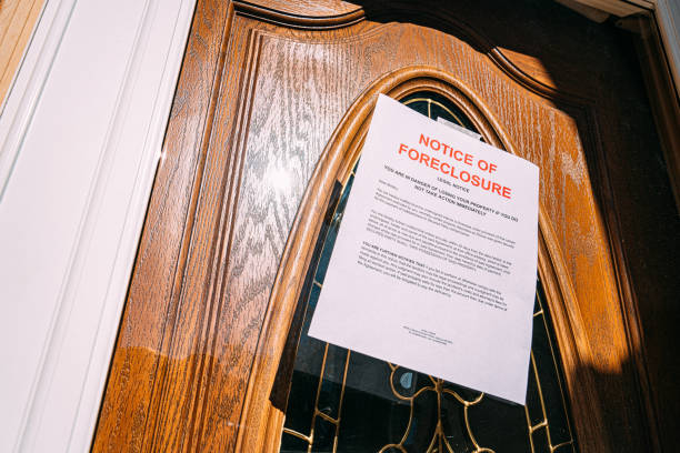 Paper Foreclosure Notice Taped to the Glass Front Door of a Home in a Residential Suburban Neighborhood Low Angle Shot of a Paper Foreclosure Notice Taped to the Front Door of a Home in a Residential Suburban Neighborhood foreclosure stock pictures, royalty-free photos & images