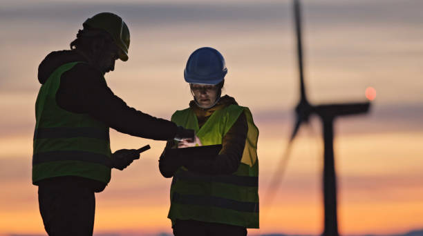 ingenieros de energía eólica trabajando en parque eólico al atardecer. sistemas de energías renovables. carbono neutralidad y energía sostenible. - maintenance engineer fotografías e imágenes de stock