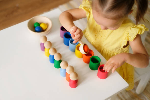 色付きのカップとシリンダーは、子供の前に行に配置されています - fine motor skills ストックフォトと画像