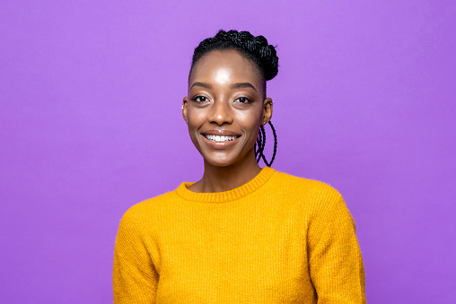 Casual African American woman smiling in purple studio isolated background