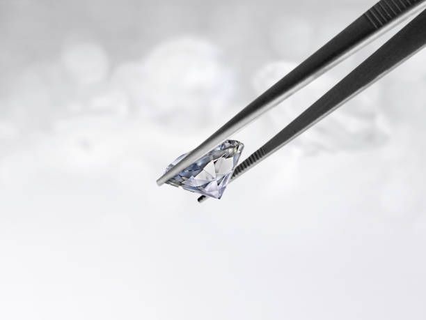 istock Diamond in tweezers on white shining bokeh background. concept for chossing best diamond gem design 1354526256
