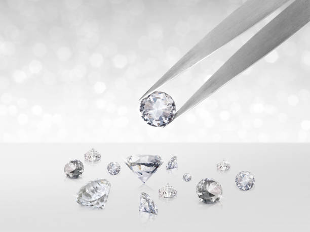 istock Diamond in tweezers on white shining bokeh background. concept for chossing best diamond gem design 1354526262
