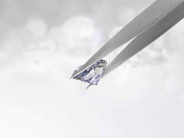 istock Diamond in tweezers on white shining bokeh background. concept for chossing best diamond gem design 1354526270