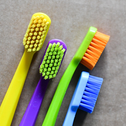Close up of four multicoloured toothbrushes on tile floor. Copy space.