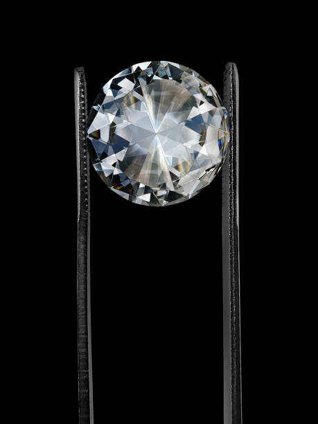 istock Diamond in tweezers on a black background with diamonds group soft focusing 1354527028