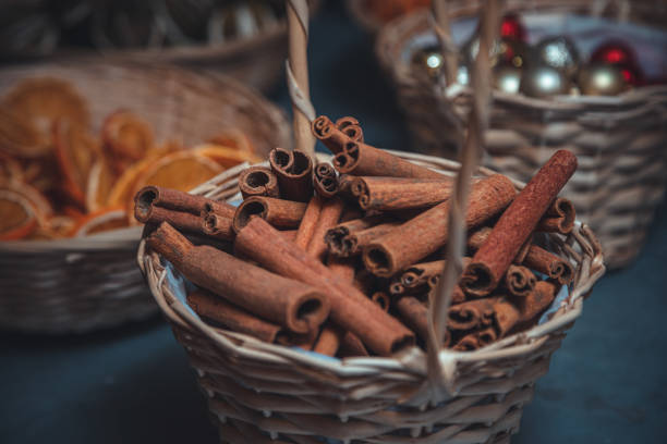 Bunch of cinnamon sticks in a straw basket on linen on dark a tabletop waiting for Christmas decoration