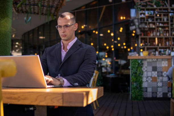 istock Young handsome businessman working on his laptop while sitting in a cafe 1354530974