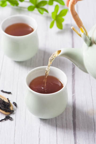 istock Pouring black tea into glass cup on wooden table 1354534515