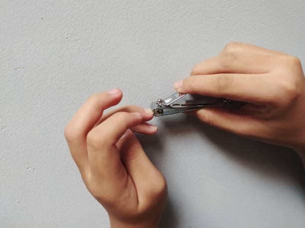 istock a boy cutting nails with nail clipper close up with light grey background 1354540649