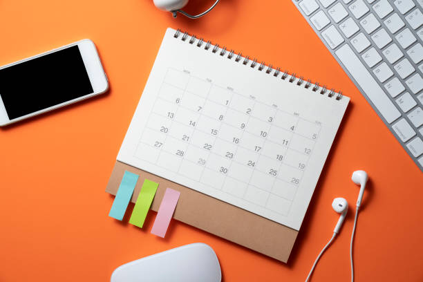 istock close up of workspace desk with calendar, smartphone, notebook, laptop or computer keyboard with orange table background, minimal style, for creative flat lay concept 1354558425