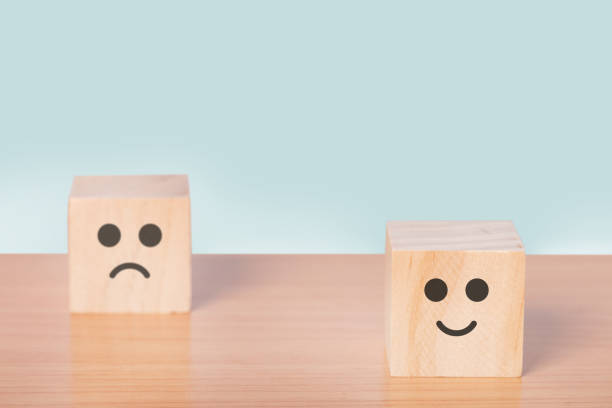istock Smiley face and blurred sad face icon on the wood cube, Customer service rating, Satisfaction survey concept. 1354559236
