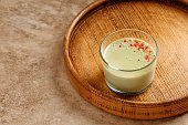Matcha panna cotta dessert with confectionery decor in a glass on a wooden tray and beige background. Minimalistic and warm photography.