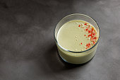 Matcha panna cotta dessert with confectionery decor in a glass on grey background. Minimalistic.