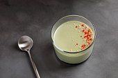 Matcha panna cotta dessert with confectionery red decor in a glass on grey background. Minimalistic.