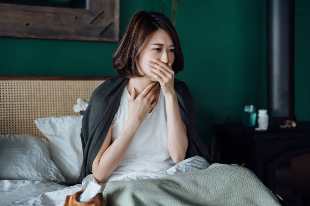 young asian woman feeling sick, suffering from sore throat, feeling sore and hurt, staying at home and resting on bed - one person women human pregnancy beautiful imagens e fotografias de stock