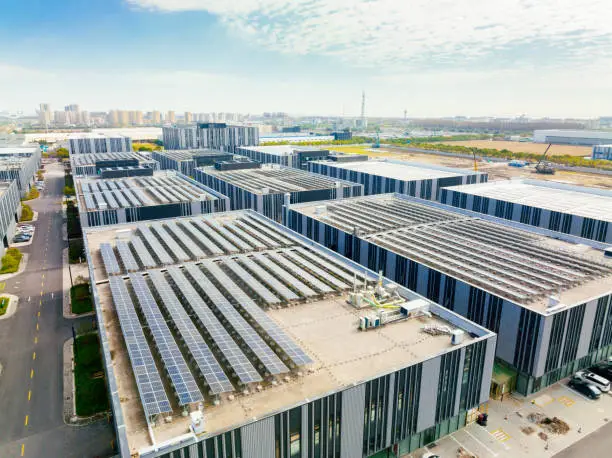Photo of Aerial view of solar panels on factory roof. Blue shiny solar photo voltaic panels system product.
