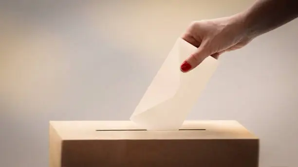 choice concept. Female voter throwing her ballot at the ballot box