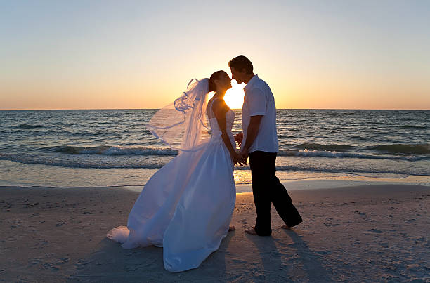 sposa & sposo sposi baciare al tramonto sulla spiaggia - wedding beach bride groom foto e immagini stock