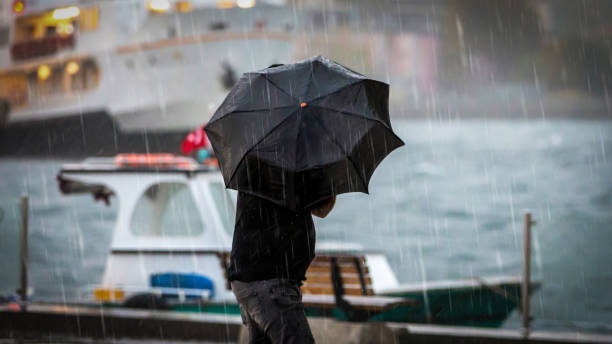 mann hält regenschirm - storm stock-fotos und bilder