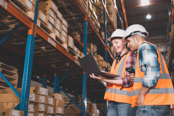 Two logistic staff in safety suite working at warehouse stock photo