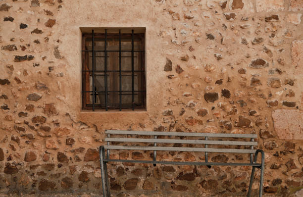 istock Metal bench against stone wall with window 1354585704