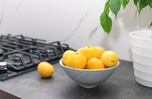 closeup of fresh citrus fruits in ceramic bowl on kitchen countertop at modern house. healthy vitamin food concept