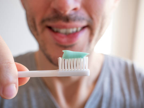 istock Young man smiles while brushing his teeth, man holds toothbrush with toothpaste in hand, healthy oral hygiene habits 1354588673