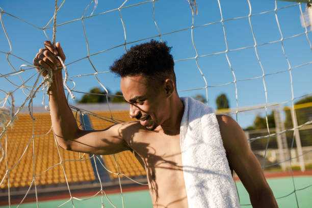 retrato de desportista afro-americano sem camisa com toalha no ombro em gol de futebol após jogo no estádio da cidade - football player - fotografias e filmes do acervo