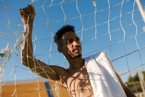 young shirtless african american sportsman with towel on shoulder standing in football goal after game at city stadium - football player imagens e fotografias de stock