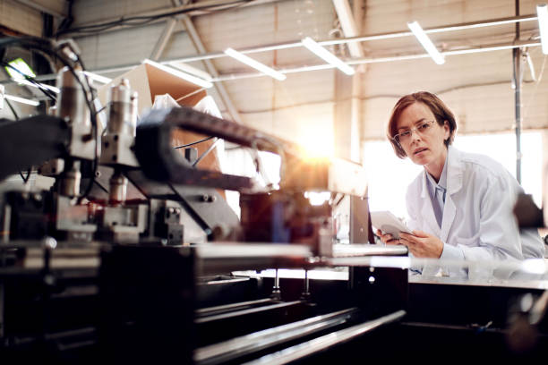 istock Female executive working at factory with machines 1354611879