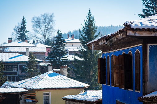 Snow-covered street among old houses on a sunny winter day in the ancient town of Koprivshtitsa, Bulgaria