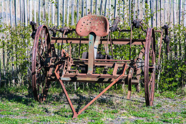 istock Old-fashioned, rusty agricultural machine in front of a fence. 1354614214