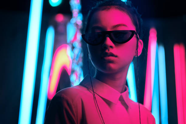 Teenage asian girl in sun glasses in neon light Portrait of young asian teenage girl in stylish crescent shaped sun glasses, in red anf blue neon light. Cyber, futuristic portrait concept artificial neural network photos stock pictures, royalty-free photos & images