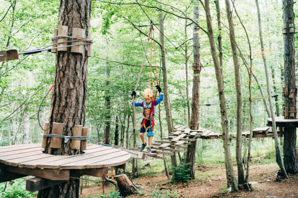 istock Boy walking across the agility bridge holding on to the security ropes 1354617797