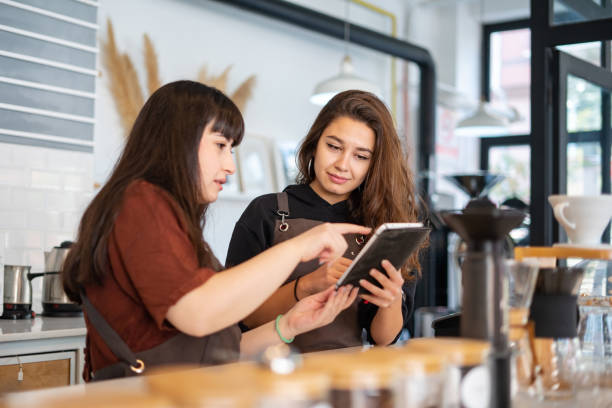 istock Two female barista having a conversation and using tablet at coffee shop 1354639219