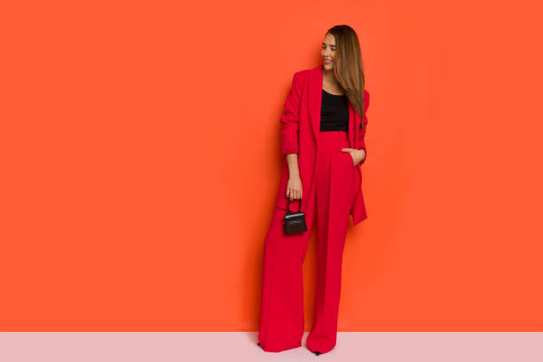 Fashionable young woman is posing in red jacket and baggy pants. stock photo