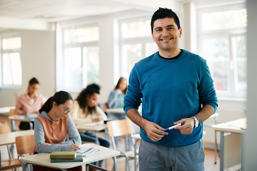Retrato de un feliz profesor de secundaria en el aula mirando a la cámara. photo