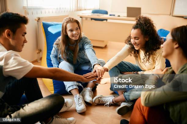 Happy High School Students Gathering Their Hands In Unity During A Break In The Classroom Stock Photo - Download Image Now