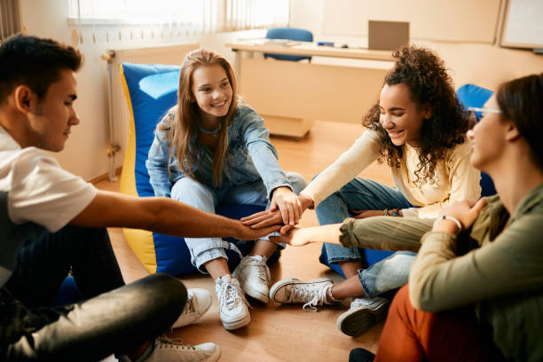 happy high school students gathering their hands in unity during a break in the classroom. - interior teens bildbanksfoton och bilder