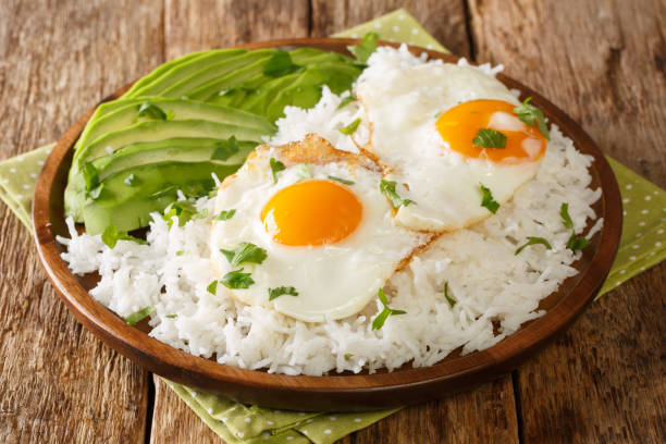 istock Boiled rice on top with fried eggs served with fresh avocado close-up in a plate. horizontal 1354641433
