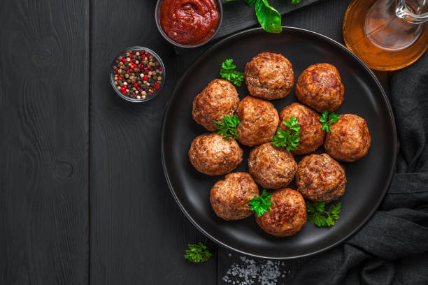 istock Fried meatballs with basil in a black plate on a dark background 1354643835