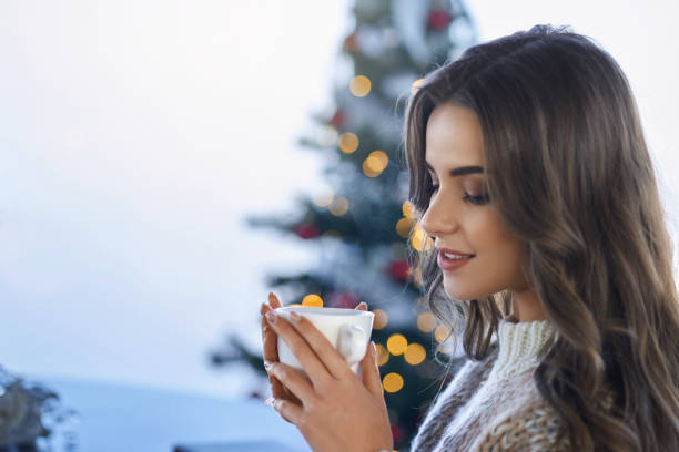 istock Charming lady holding cup of hot beverage at home 1354651188