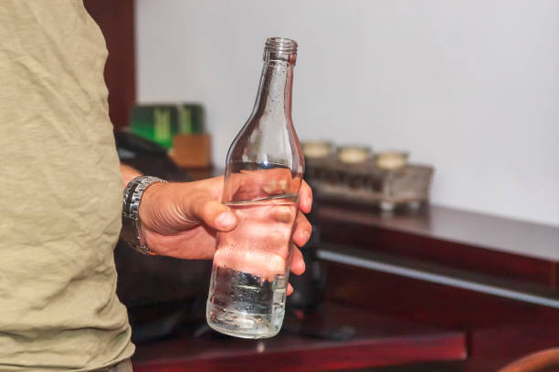istock Male hand holding a glass with white transparent liquid. 1354662748