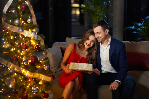 Smiling man and woman sharing with christmas gifts at home stock photo