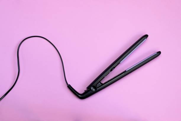 plancha de pelo negra con cordón aislado sobre fondo rosa - straightener fotografías e imágenes de stock