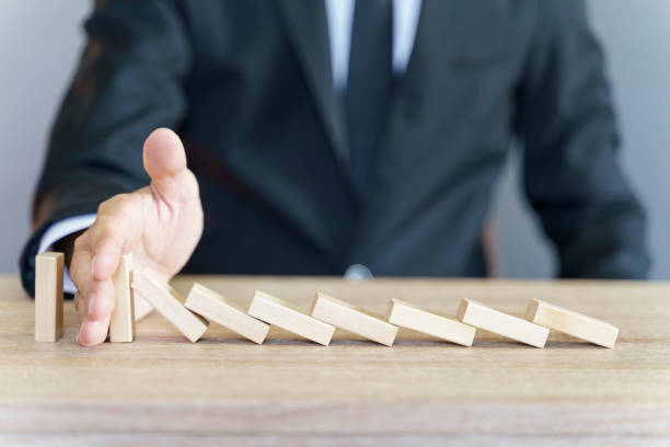 istock Man stopping domino effect on wooden table 1354674831