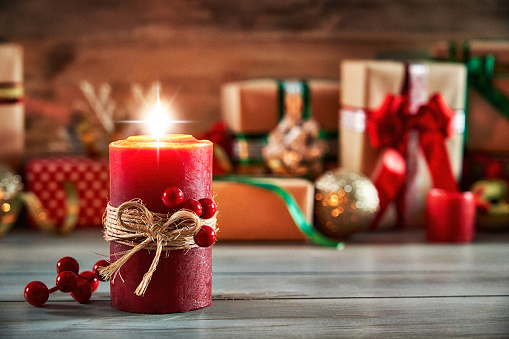 Christmas concepts: Red candle with Christmas presents on rustic background with copy space.