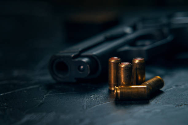 istock Gun with cartridges on dark concrete table. 1354680880