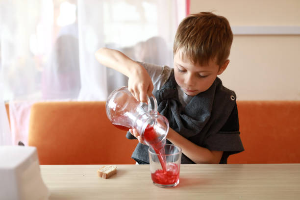 ジュースをガラスに注ぐ少年 - juice carafe glass decanter ストックフォトと画像